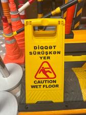 Sürüşkən yer xəbərdarlıq lövhəsi – “Diqqət: Sürüşkən yer / Caution Wet Floor”